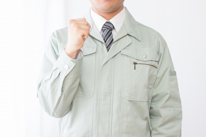 ガッツポーズをする作業服の男性