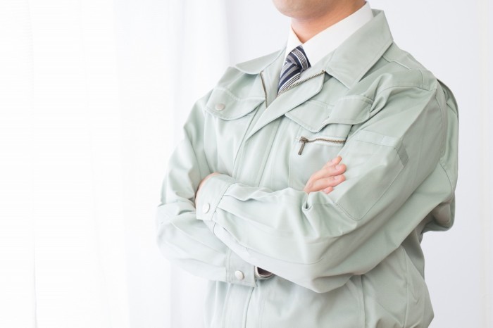 腕を組む作業服の男性