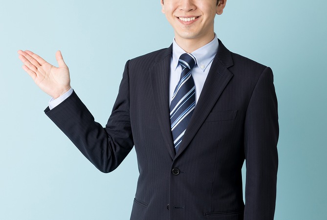 手を横に出しているスーツの男性